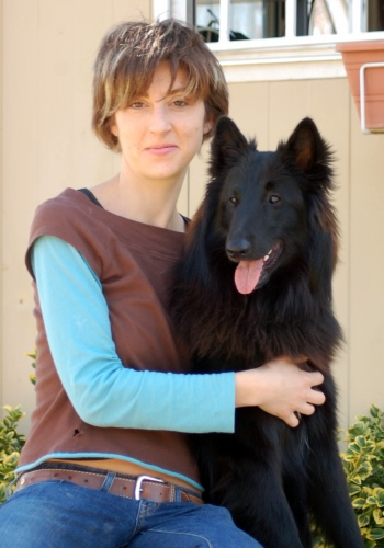 Dona amb gos de pèl llarg negre somrient.
