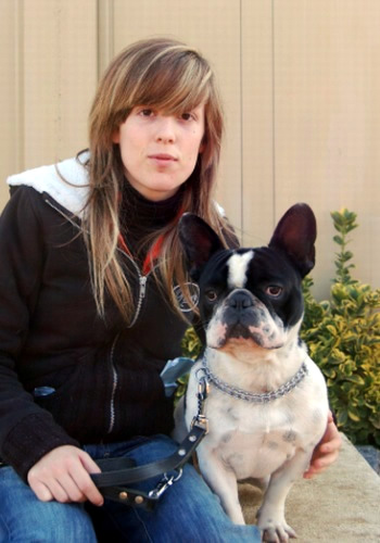 Dona amb gos bulldog francès asseguts en exterior.