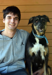Home jove amb gos somrient al costat.