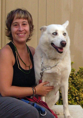 Dona somrient amb gos de pel blanc.