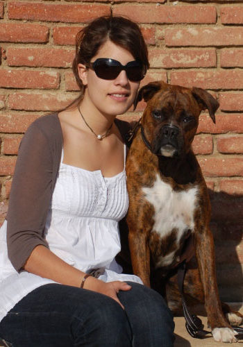 Dona amb gos boxer asseguts al sol.