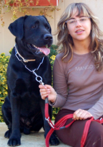 Dona jove amb el seu gos labrador negre.