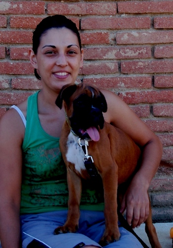 Dona somrient amb gos boxer jove.