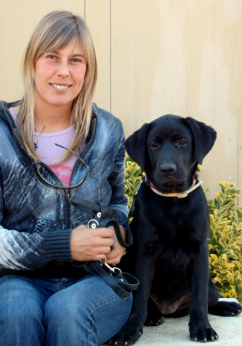 Dona somrient amb gos labrador negre.