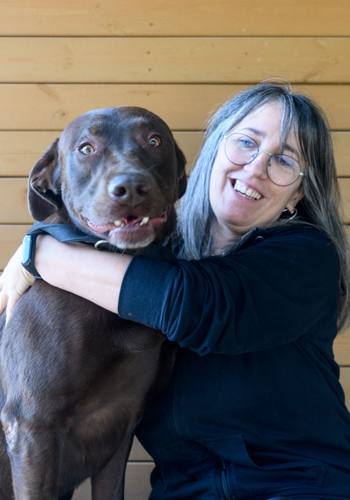 Dona abraçant el seu gos marró feliç.