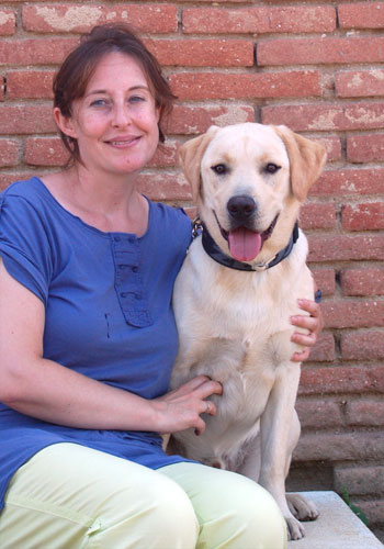 Dona asseguda amb un Labrador retriever somrient.