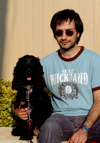 Home assegut amb gos cocker i ulleres de sol.