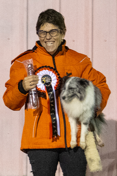 Dona amb gos i premi en concurs caní.